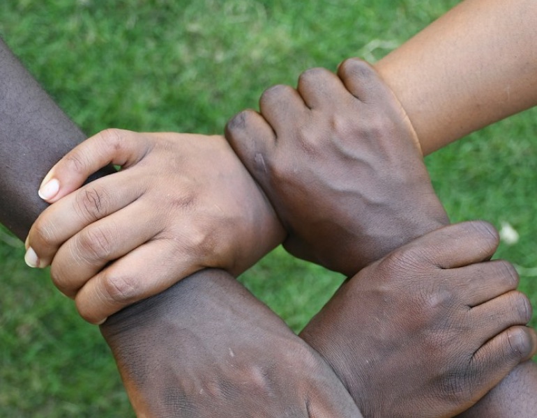 Four hands clasping one another’s wrists in a chain