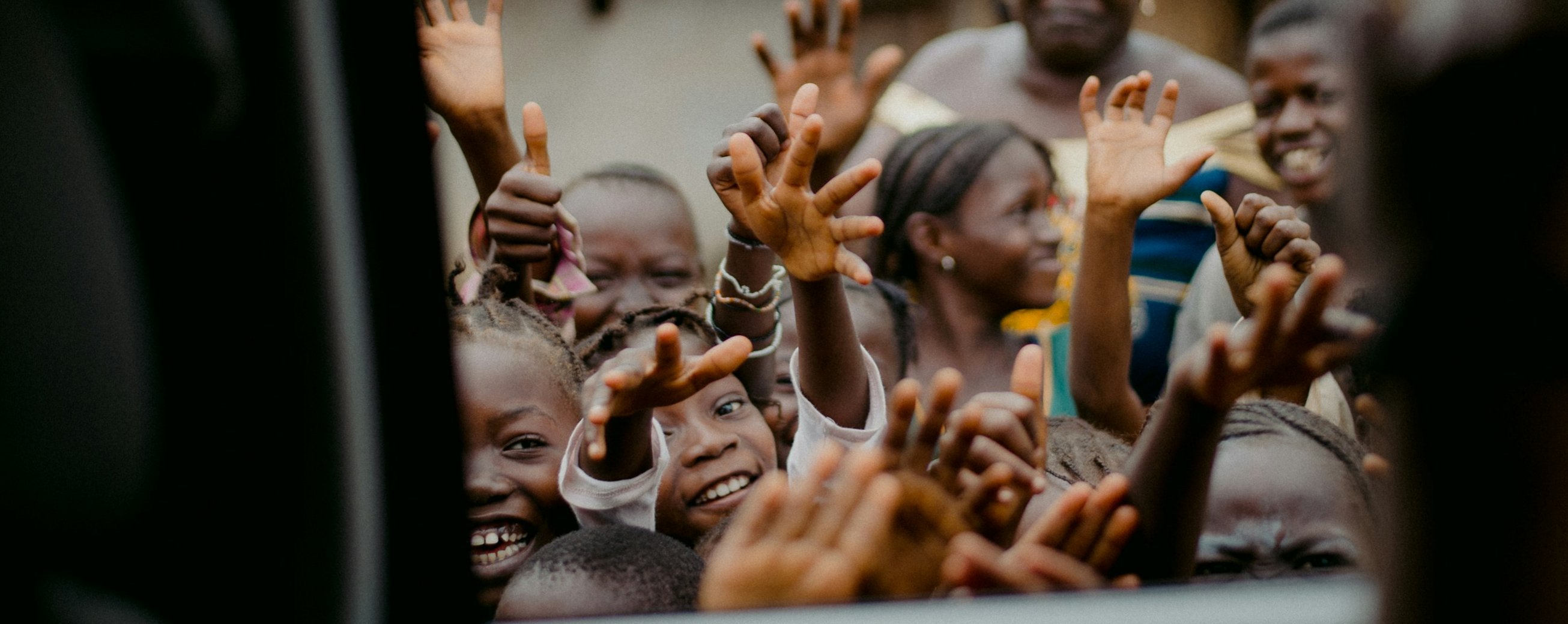 Children and community members waving in welcome